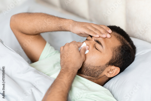 Sick african american man lying in bed, got flu