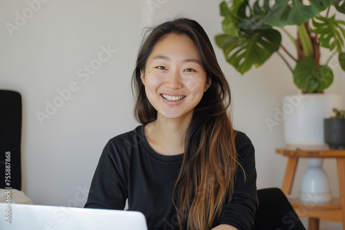 Woman smiling in front of laptop, working from home office