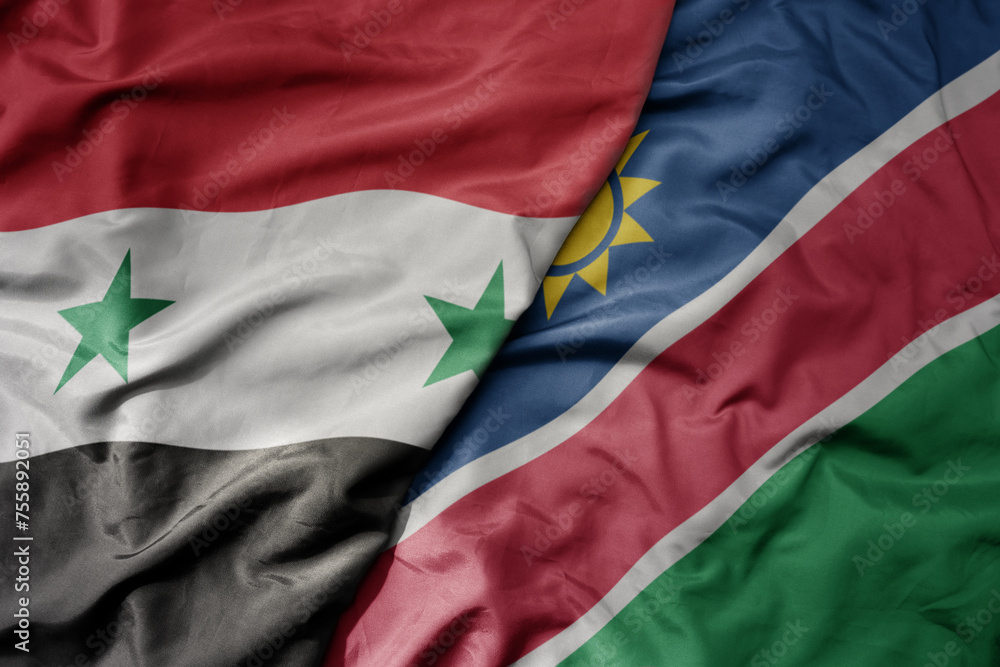 big waving national colorful flag of namibia and national flag of syria .