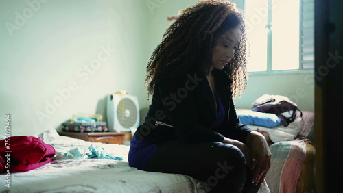Slika na platnu Concerned African American woman seated by bedside looking down with pensive wor