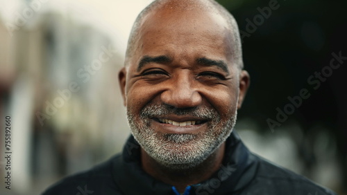 One happy middle-aged man smiling at camera close-up face. Portrait of a 50s person of African descent standing in urban street