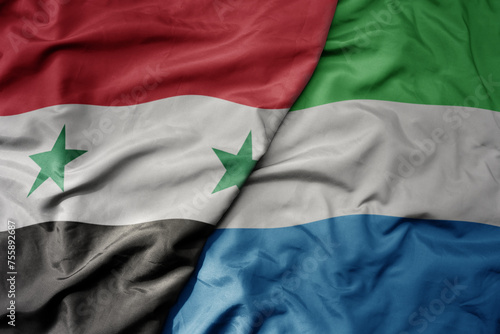 big waving national colorful flag of sierra leone and national flag of syria .