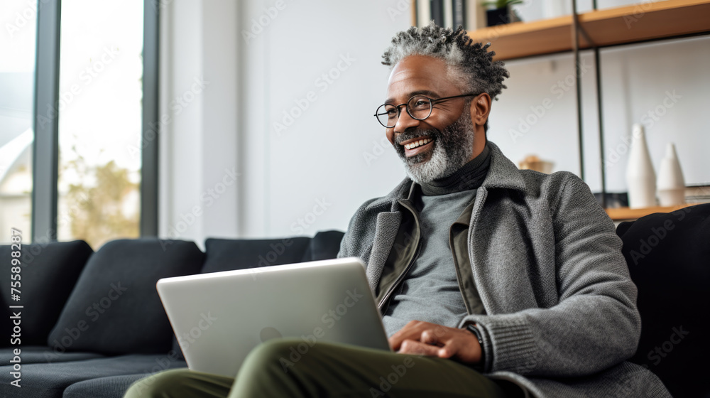 Man smiling while working on a laptop in a modern office environment Man smiling while working on a laptop in a modern office environment