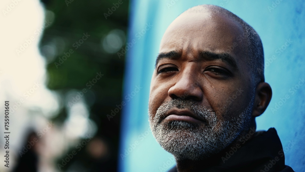 Serious Middle-aged South American hispanic black man close-up face looking at camera in urban environment. Gray hair bearded bold 50s person portrait with concerned expression