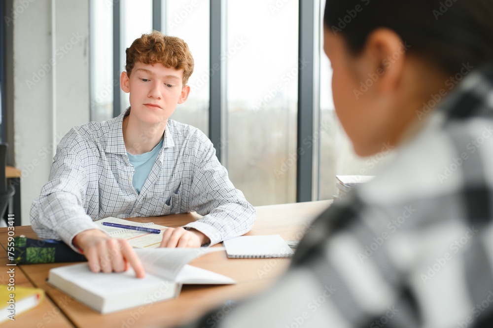 students sit at shared desk making notes studying together at university students sit at shared desk making notes studying together at university