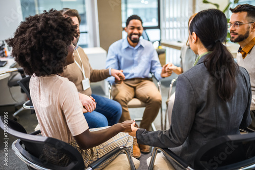 Group of people sitting in a circle holding hands and participate in a support meeting. Healthcare and medicine concept.