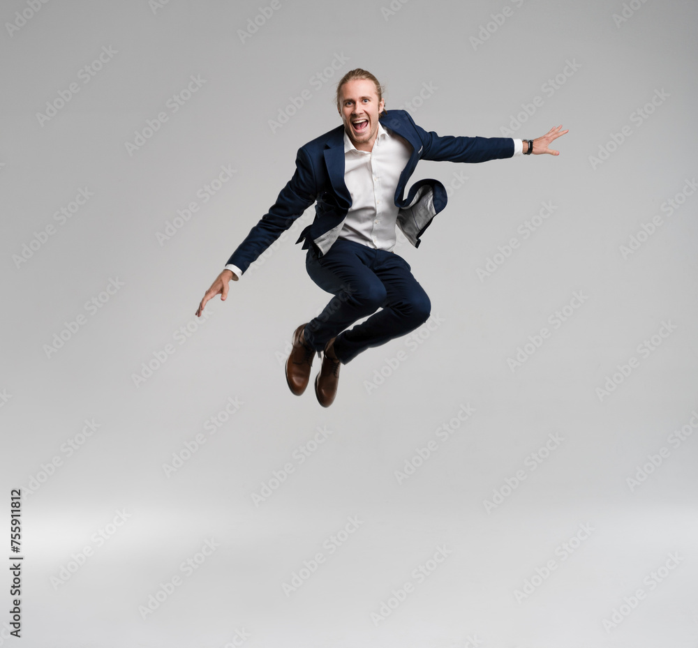 Full length business man in black suit jumping in studio isolated on a white background.