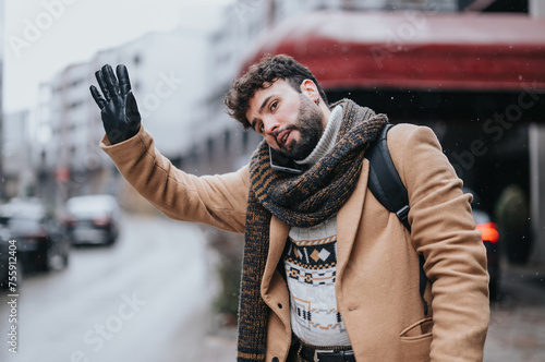 Elegantly dressed young man waving for a cab on a wintery day. He's outdoors, displaying a sense of urgency and determination amidst snowflakes.