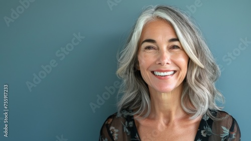 A woman of fifty years old smiles close-up on a blue background. Happy old age, healthy teeth. photo
