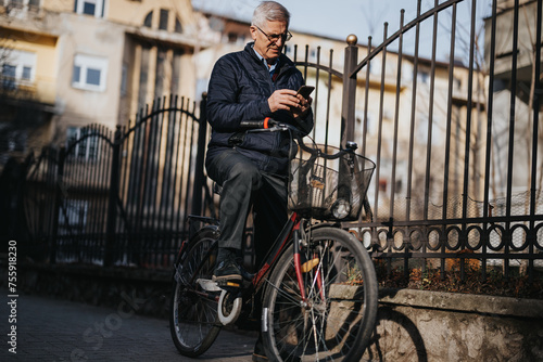 Active elderly gentleman pauses on his bike ride to check his mobile phone, exemplifying modern senior lifestyle and technology use.