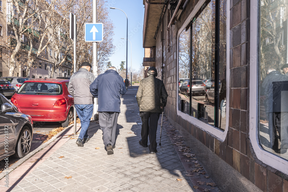 A group of older people walking on a sidewalk in the city
