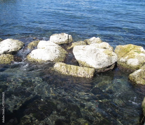 Sun-bleached boulders in water by the pier