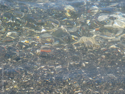 Water ripples over sand and stone