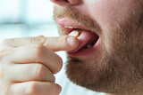 Close-up of man's mouth taking pill, medicine to be healthy. Drug addiction, stay healthy, and do what your doctor says.	