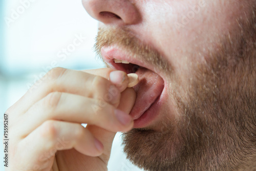 Tableau sur toile Close-up of man's mouth taking pill, medicine to be healthy