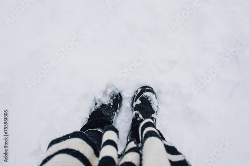 looking down at snow boots, black and white scarf in the snow