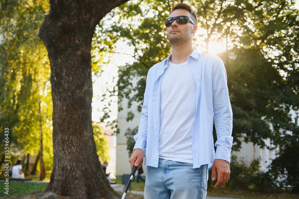 Young handsome blinded man walking with stick in town Young handsome blinded man walking with stick in town