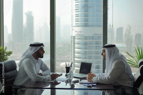 Two middle eastern businessmen at a desk in a large office building. They are discussing business matters
