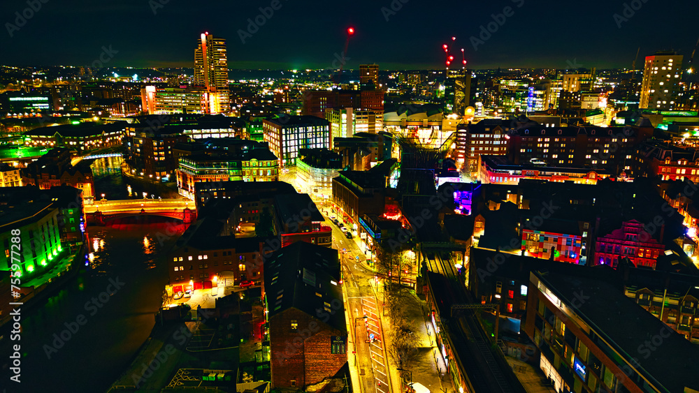 Panoramic night view of a bustling cityscape with illuminated streets and skyscrapers in Leeds, UK.