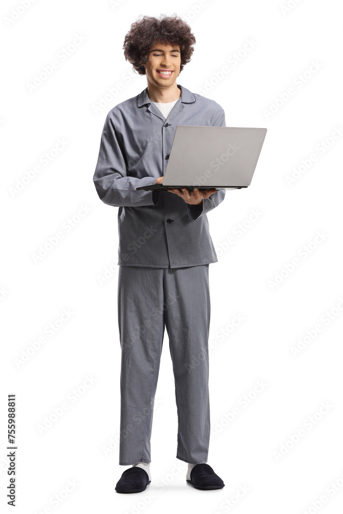 Young man in pajamas standing and using a laptop computer Young man in pajamas standing and using a laptop computer