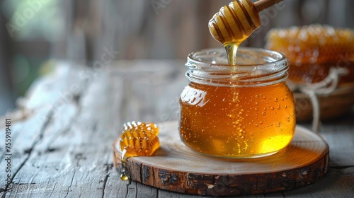 An aromatic honey is poured into a glass jar with a wooden stick against a white background.