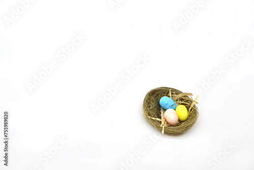 Small model nest with three coloured eggs isolated on a white background. Copy space. Easter theme.