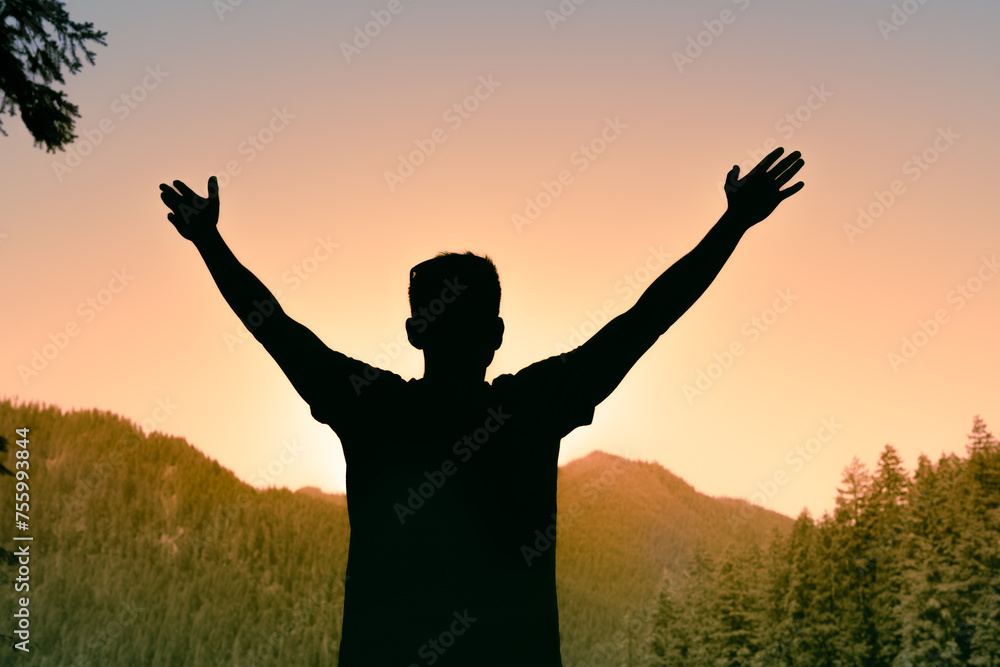 Happy carefree joyful man standing in the mountains with arms up to the sky feelings of joy freedom in nature 