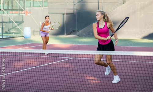 Young woman in skirt playing tennis on court. Racket sport training outdoors.