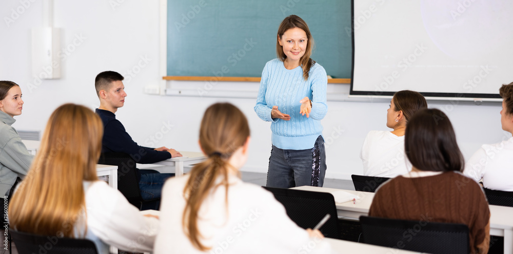 Fototapeta premium Positive adult female teacher leading a lecture in the classroom