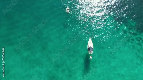 toma cenital área con dron de un yate fondeado en las transparentes aguas del mar mediterráneo en Mallorca. El dron sube lentamente abriéndose el campo de visión. photo