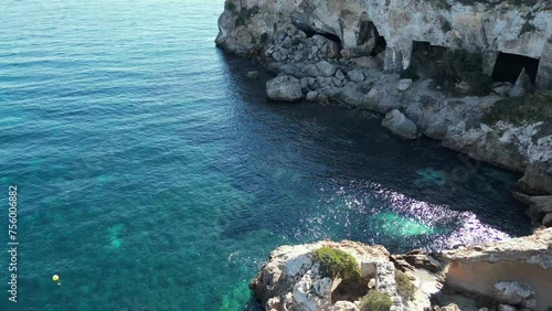 Vista aérea estática de las cuevas de la playa del mago en Mallorca.  Agua transparente, yates e embarcaciones fondeados. Dia de sol en verano. photo