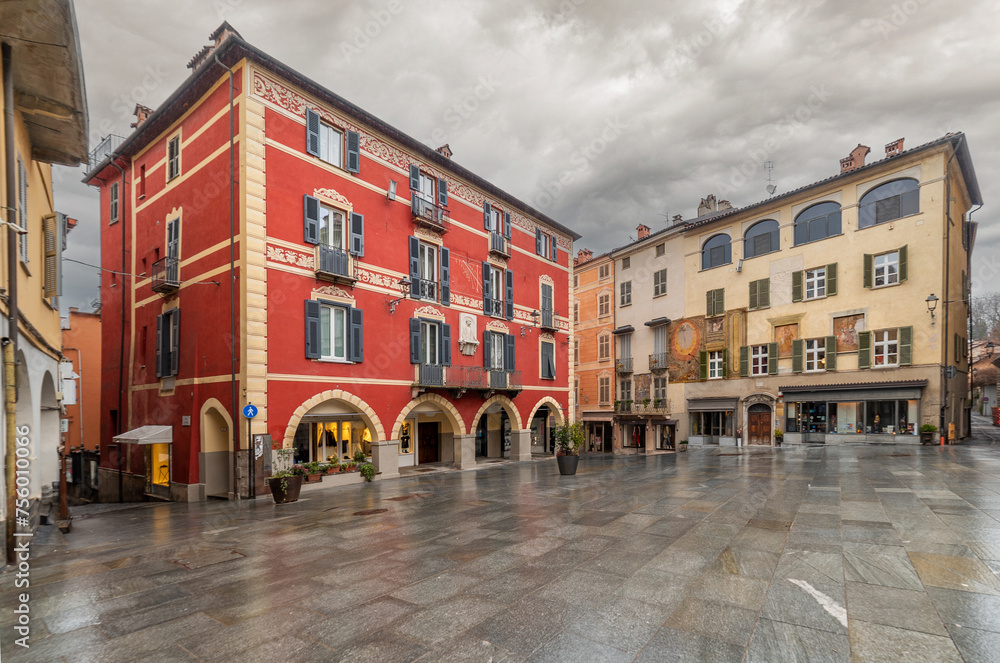 Mondovi, Italy - March 09, 2024: St. Peter's Square, view of the historic buildings decorated with arcades and the square paved with stone slabs on a rainy day