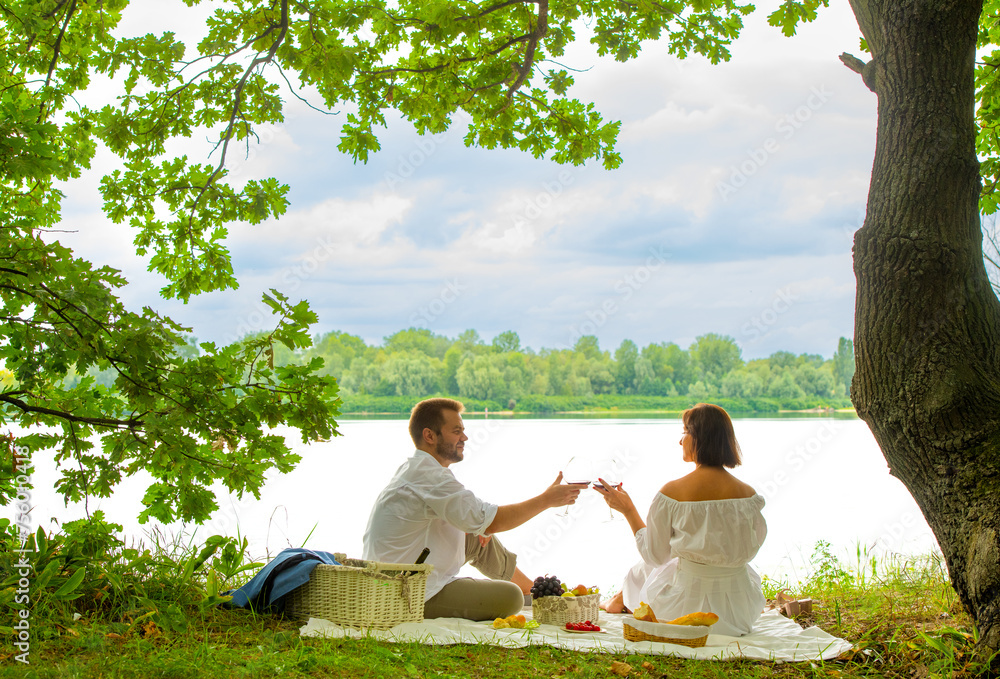 summer landscape with a couple on a picnic. the couple spends time together on a picnic on the river bank