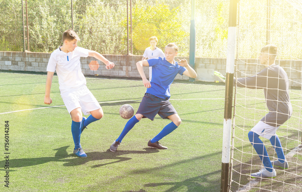 Youthful football players challenging for ball in goalmouth zone