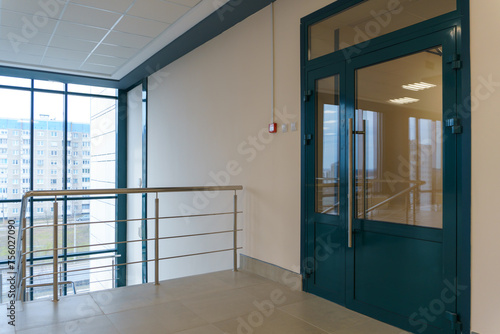 An empty spacious room of a modern office building with large windows. An empty hall with columns and a new renovation. Interior design. Suspended ceiling and square LED lamps.