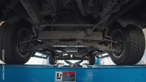 Camera span under suspended car on lift in auto service bay, inspection of the undercarriage. photo