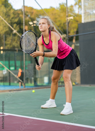 Portrait of concentrated sporty girl with tennis racquet and ball in her hands standing and ready to play match standing © JackF