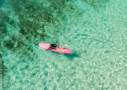 woman paddling on a surfboard in clear ocean water,