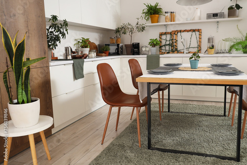 Interior of modern kitchen with green plants, dining table and counters