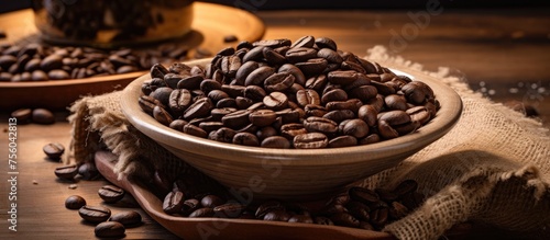 A bowl of coffee beans, a crucial ingredient for making coffee, rests on a wooden table beside a cup of freshly brewed coffee