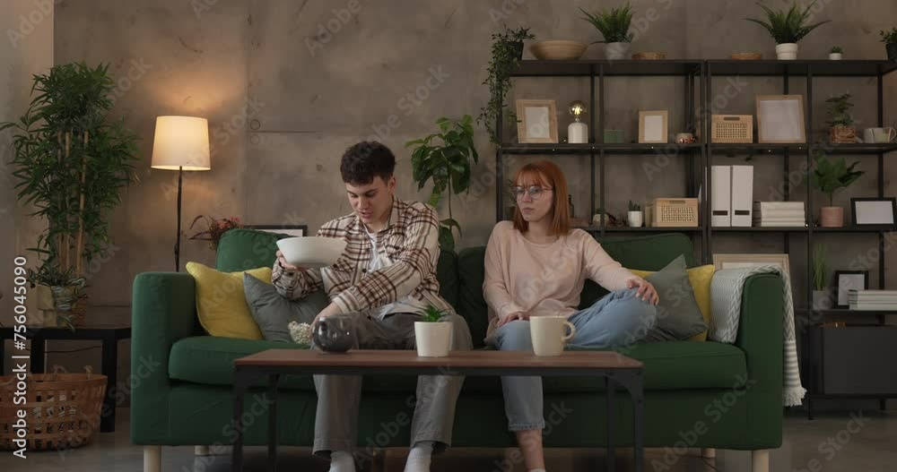 Couple caucasian man and woman sit at home on sofa bed watch tv movie Couple caucasian man and woman sit at home on sofa bed watch tv movie