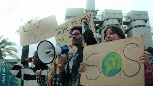 Group of diverse people shouting angrily outdoor manifesting for global warming. Pro-earth demonstration with banners for climate change. Man with megaphone in a protest against pollution in community photo