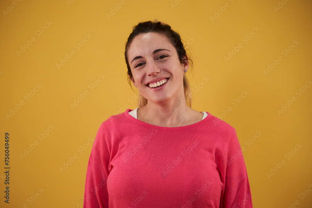 Portrait of a young caucasian woman looking at camera with toothy smile, isolated in a yellow background. Copy space. Portrait of a young caucasian woman looking at camera with toothy smile, isolated in a yellow background. Copy space.