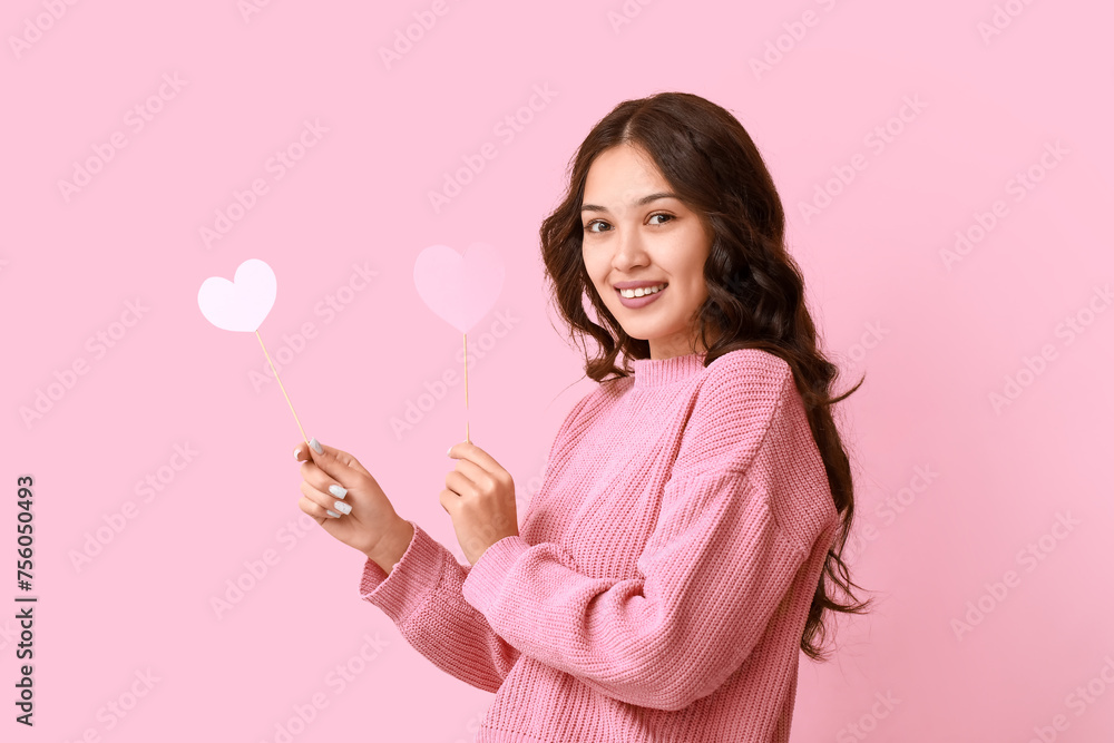 Happy young Asian woman with pink paper hearts on color background. Valentine's Day celebration Happy young Asian woman with pink paper hearts on color background. Valentine's Day celebration