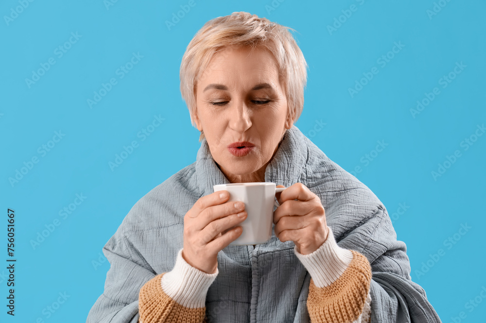Mature woman with plaid and cup of hot tea on blue background, closeup Mature woman with plaid and cup of hot tea on blue background, closeup
