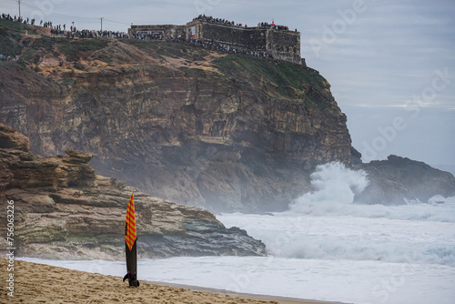 crowd of spectators watching the big wave surfers on the famous cliffs at the lighthouse at Nazaré Praia do Norte