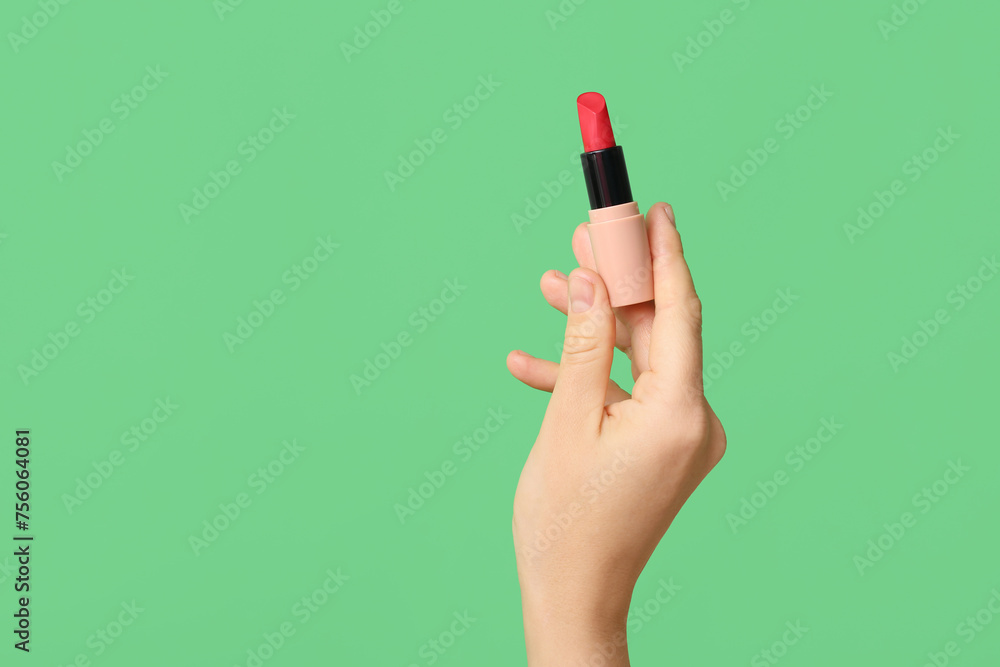 Hand holding red lipstick on green background Hand holding red lipstick on green background