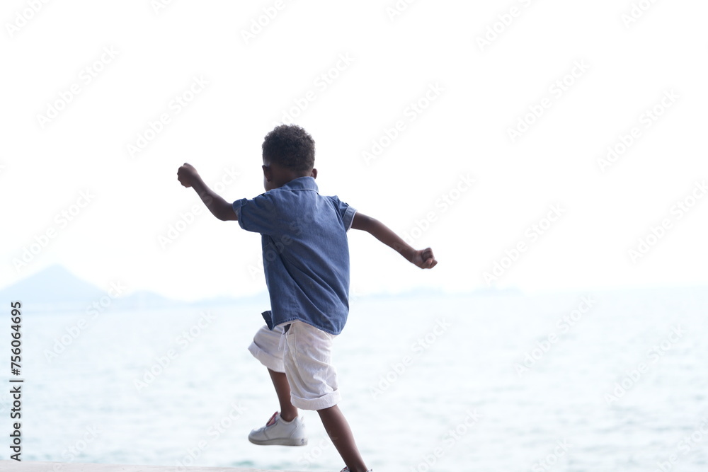 Mixed race African and Asian boy is playing at the outdoor area. smiling happy boy has fun running on the beach. portrait of boy lifestyle with a unique hairstyle. Mixed race African and Asian boy is playing at the outdoor area. smiling happy boy has fun running on the beach. portrait of boy lifestyle with a unique hairstyle.
