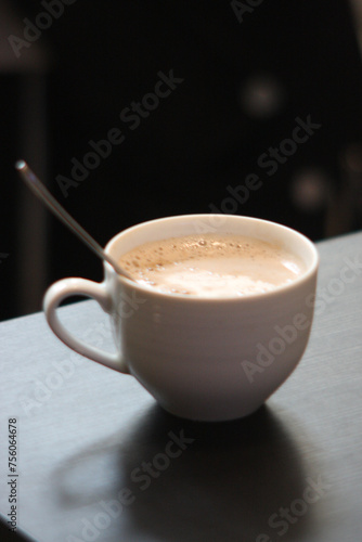 Cup of coffee or chai with spoon on table