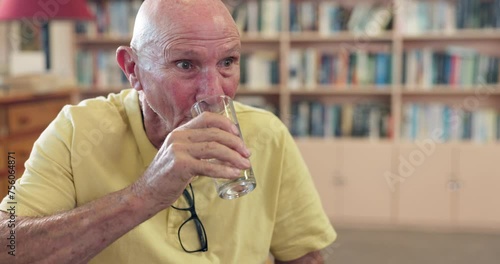 Healthy, elderly or man drinking water for wellness or hydration to relax with arthritis in a library. Parkinson, tremor or thirsty senior male person with a glass or fresh h2o liquid for vitality photo